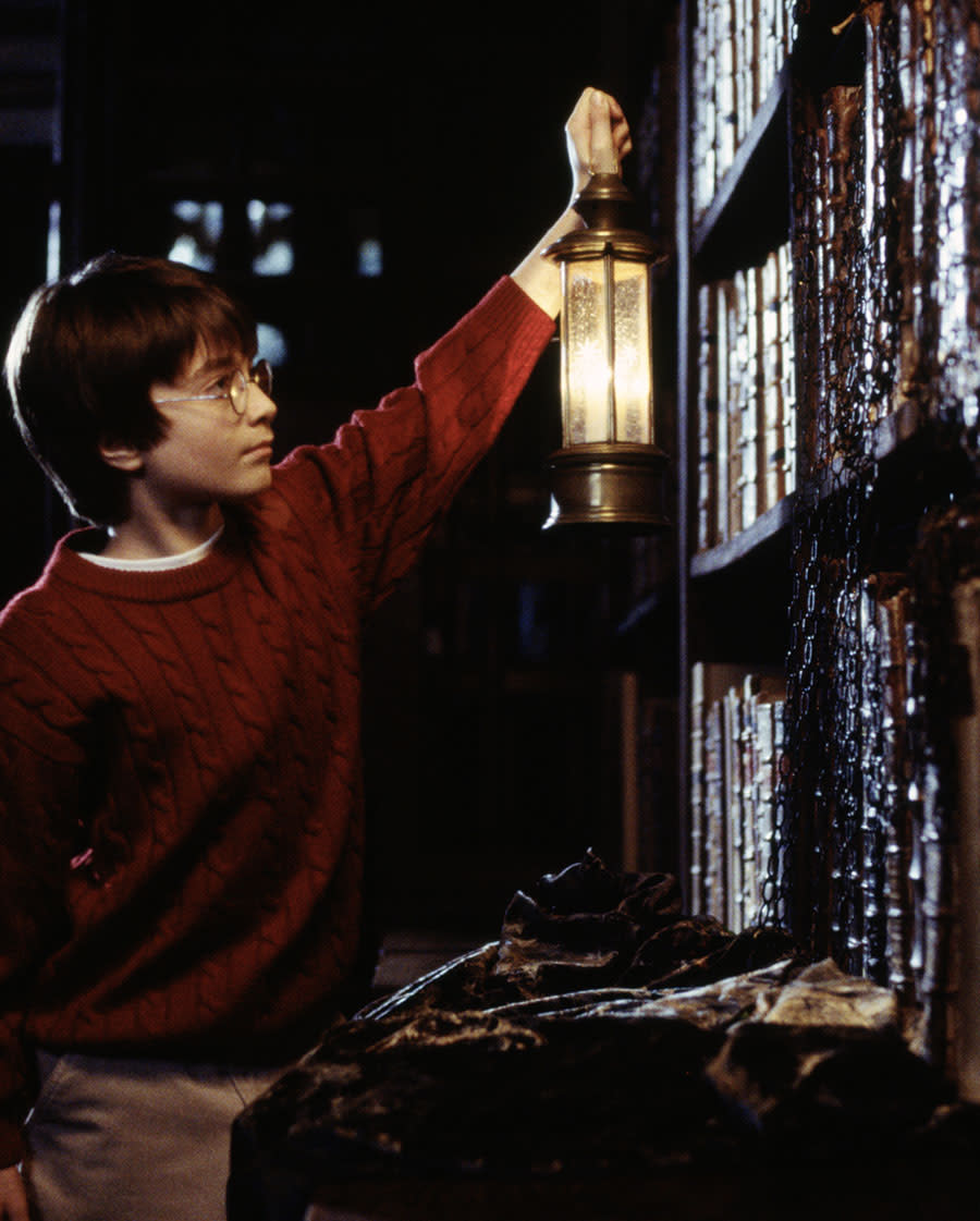 Harry Potter holding lantern up to bookshelf meme template